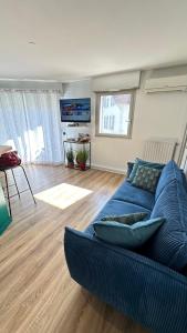 un soggiorno con divano blu e pavimenti in legno di Cocon douillet résidence calme a Pau