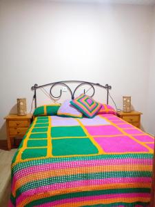 Una cama con una manta colorida y almohadas. en Villa Mina, en Minas de Riotinto