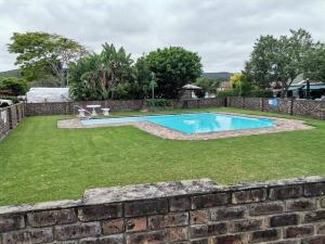 a swimming pool in a yard next to a brick wall at Keurbooms river, San Marino Complex (Unit 53), Self-catering (Plettenberg Bay) in Keurboomstrand