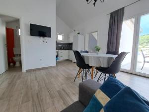 a living room with a table and chairs and a kitchen at Apartment Teuta in Žirje