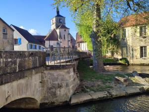 a bridge over a river in a town with a church at La Vignotte in Bèze +3 photos