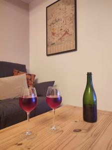 two wine glasses on a wooden table with a bottle of wine at La Vignotte in Bèze
