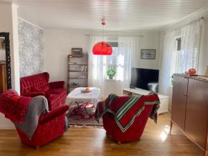 a living room with two red chairs and a tv at Nära Kvarnen-Mollösund in Mollösund