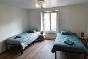 two twin beds in a room with a window at Le Repose Pieds - Gîte d'étape randonnées - in Le Monastier sur Gazeille