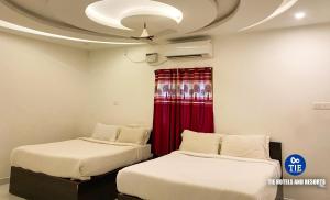 two beds in a room with a ceiling fan at La Paradise Luxury in Puducherry