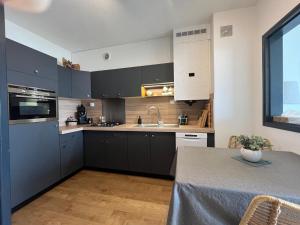 a kitchen with black cabinets and a table and a window at Cœur de Concarneau, appartement entier, proche centre, corniche et plage avec parking in Concarneau