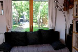 a couch with pillows in front of a window at Maison en bois au fond du jardin in Fontenay-sous-Bois +6 photos