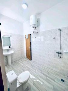 La salle de bains est pourvue de toilettes, d'un lavabo et d'une douche. dans l'établissement Charly-duplexben, à Cotonou