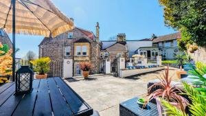 an outdoor patio with a wooden table and an umbrella at All Seasons Bed & Breakfast - Adults Only in Weston-super-Mare