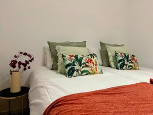 a bed with white sheets and pillows and a vase at Misterhost Triana Remedios 2BR & parking in Seville