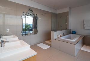 a white bathroom with two sinks and a mirror at Lavender Dreams - Villa 111 in Hermanus