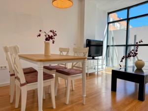 a dining room with a table and chairs and a tv at Misterhost Triana Remedios 2BR & parking in Seville