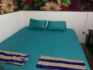 een blauw bed met twee blauwe kussens erop bij Amigos Inn in Trincomalee