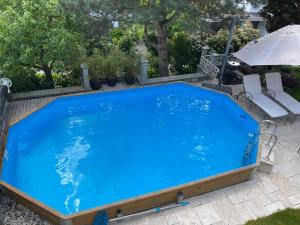 uma grande piscina azul com cadeiras e um guarda-sol em Villa Musica em Lenzburg
