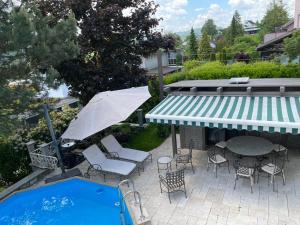 倫茲堡的住宿－Villa Musica，一个带桌子和遮阳伞的庭院,毗邻一个游泳池