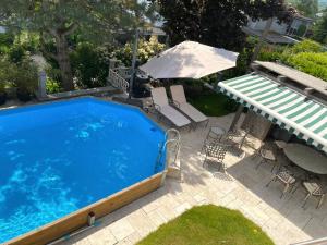 a swimming pool with a umbrella and a table and chairs at Villa Musica in Lenzburg