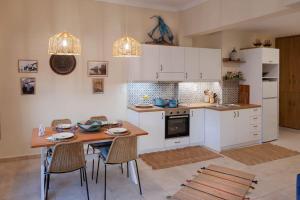 a kitchen with white cabinets and a wooden table and chairs at Casa Artemisia in Kalymnos +17 photos
