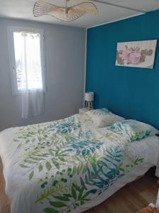 Ce lit se trouve dans une chambre dotée d'un mur bleu. dans l'établissement Duplex face océan T2 + mezzanine à Bretignolles sur mer, à Bretignolles-sur-Mer