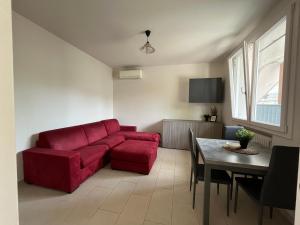 a living room with a red couch and a table at Azzurro Horizon Apartment in Bellaria-Igea Marina