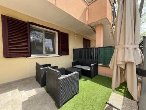 a patio with chairs and a patio umbrella and grass at Azzurro Horizon Apartment in Bellaria-Igea Marina