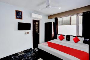 sypialnia z łóżkiem z czerwonymi poduszkami i oknem w obiekcie Collection O Mount Olympus Hotel w mieście Indirapuram