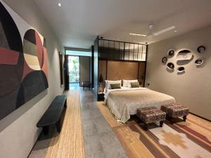 a bedroom with a large bed and a bench at Soul Nest-Pyramid Valley International Bengaluru in Bangalore