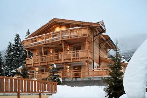 a large log cabin in the snow with a deck at Chalet Fabriel in Montgenèvre