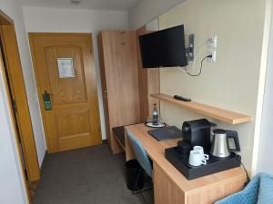 a room with a desk with a coffee maker and a television at Hotel Landgasthof Blume in Lichtenau
