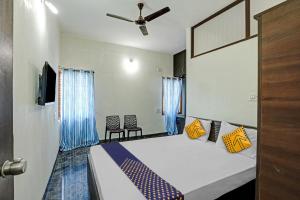 1 dormitorio con 1 cama con almohadas azules y amarillas en SPOT ON Sri Durga Residency Hd Kote, en Mysore
