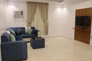 a living room with a blue couch and a tv at طيف المكان للشقق الفندقية in Riyadh