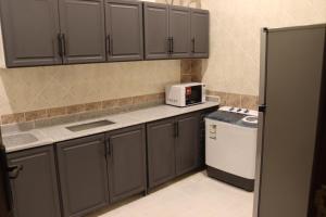 a kitchen with gray cabinets and a white appliance at طيف المكان للشقق الفندقية in Riyadh