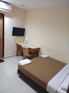 a bedroom with a bed and a desk with a computer at KL CITY LODGE in Kuala Lumpur
