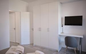 a room with white cabinets and a desk and a tv at Il Castello Suites in Avlemonas