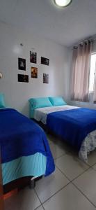 2 letti in una camera da letto con lenzuola blu di Apartamento Jasmim a Manaus