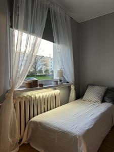 a bedroom with a bed and a window with curtains at Gdynia Apartament Torpedownia in Gdynia