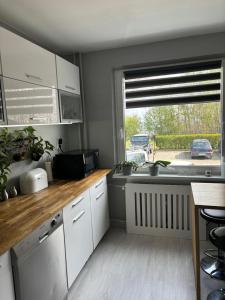 a kitchen with white cabinets and a large window at Gdynia Apartament Torpedownia in Gdynia