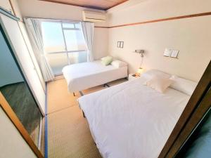 大阪市にある8人可能/部屋2つ/難波駅/大黒町駅 h503のベッド2台と窓が備わる小さな客室です。