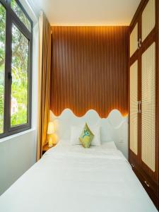 a bedroom with a white bed and a window at Căn villa Homestay 12 phòng ngủ - bể bơi - Trung tâm Bãi Cháy in Ha Long