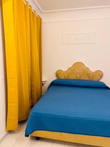 a bedroom with yellow curtains and a blue bed at Casa Alessia in Positano +11 photos