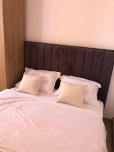 a large bed with white pillows and a black headboard at Rezidenca SHOPI in Elbasan