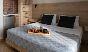 ein Tablett mit einem Getränk und Obst auf dem Bett in der Unterkunft StayInn Luxury Apartments in Nea Kallikratia