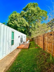 a white building with a fence next to a yard at Nomehaus shipping container studio residential neighborhood ATHENS in Athens