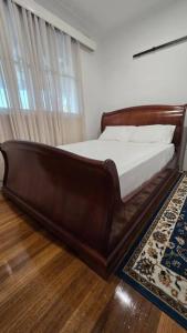 a wooden bed in a bedroom with a window at Pakenham Villa in Pakenham