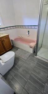 łazienka z wanną, toaletą i prysznicem w obiekcie Pakenham Villa w mieście Pakenham