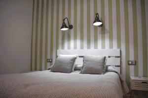 a bedroom with a bed with two pillows and two lights at Casa Rístori Calicanto in Manzanares