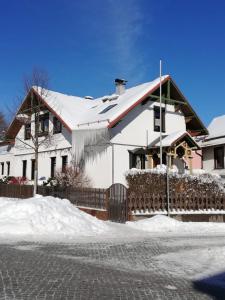 une maison recouverte de neige avec une clôture dans l'établissement Ferienhaus „Schlupfwinkel“, kostenloser Parkplatz, Vollausstattung, à Ilmenau