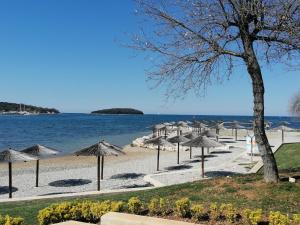 a beach with umbrellas and the water at Only 250m from the sea in Funtana +4 photos