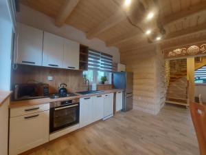 uma cozinha com armários brancos e pisos em madeira em Domek u Andrzeja 3 em Ciche