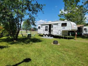 a white rv parked in a grass field at Camping Beaurivage 2-Pret à camper pour 4 personnes in Routhierville