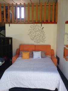 uma cama laranja com almofadas num quarto em Loft immerso nel bosco em Rivola